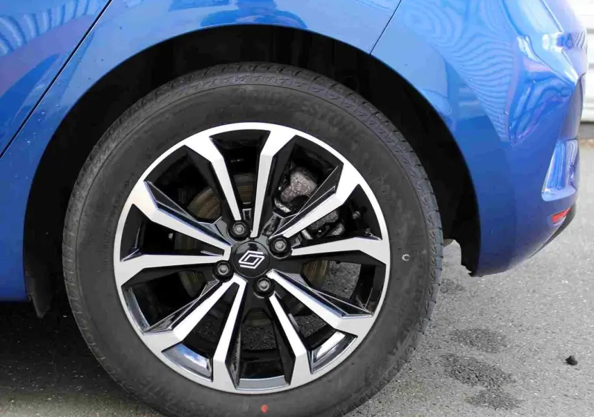 Gros plan sur la roue avant gauche de la Renault Clio bleu iron metal, mettant en valeur la jante alliage au design moderne.