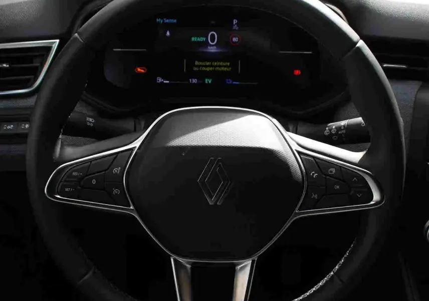 Vue rapprochée du volant noir de la Renault Clio hybride 2025 avec commandes intégrées et tableau de bord numérique.
