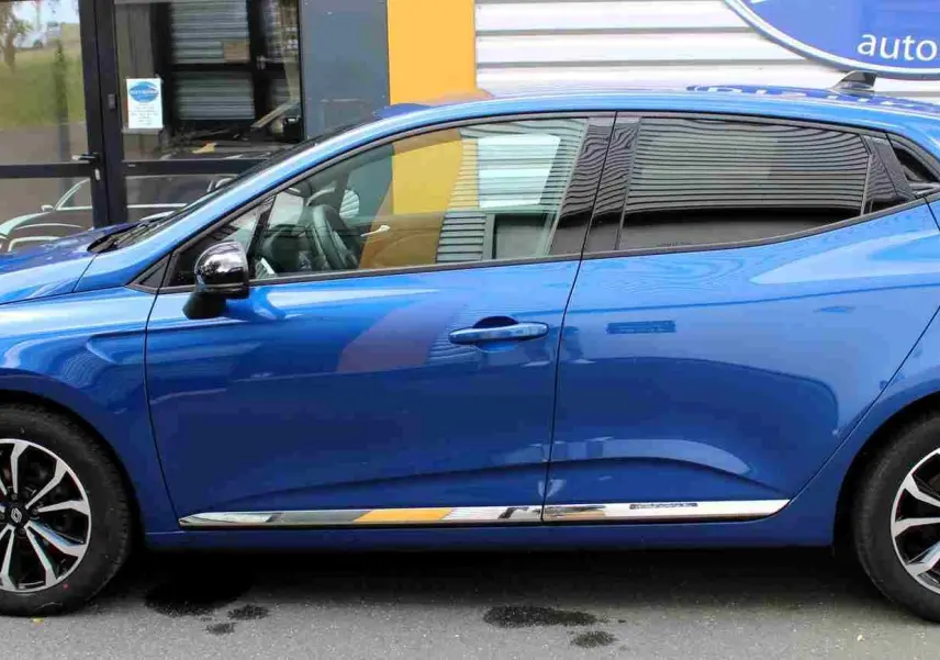 Vue intérieure avant de la Renault Clio hybride 2025, tableau de bord gris noir avec écran tactile central et volant multifonction.