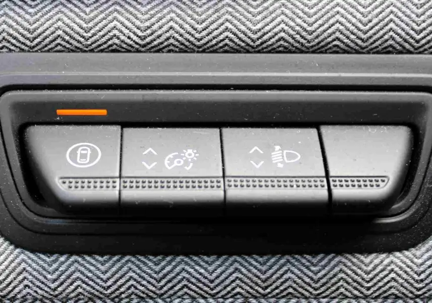 Gros plan sur les boutons de réglage d’éclairage et verrouillage dans l’habitacle de la Renault Clio hybride bleu iron metal.