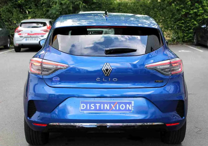 Profil droit de la Renault Clio 2025 bleu Iron Metal avec jantes alliage et vitres teintées, garée devant un bâtiment.