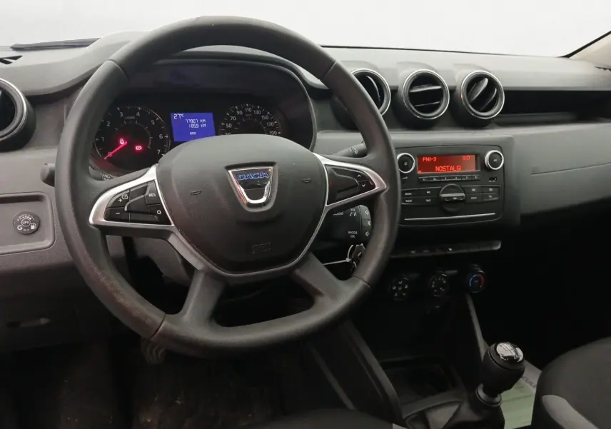 Vue intérieure centrée sur le volant noir du Dacia Duster 2021 avec tableau de bord et console radio allumée.