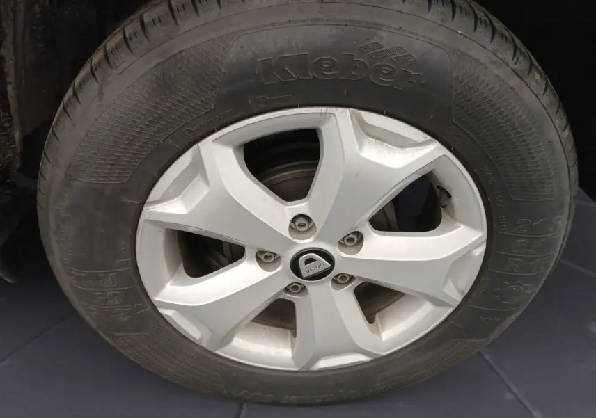 Gros plan sur la roue avant gauche du Dacia Duster blanc 4x2 Eco-G 100 Essentiel avec jante alliage et pneu Kleber.