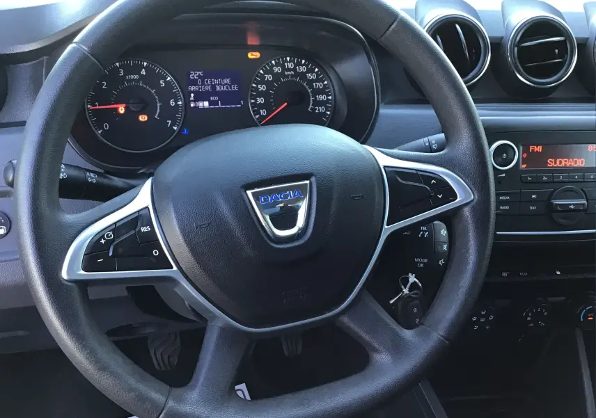 Vue intérieure centrée sur le volant noir du Dacia Duster 2021 avec tableau de bord et commandes visibles.