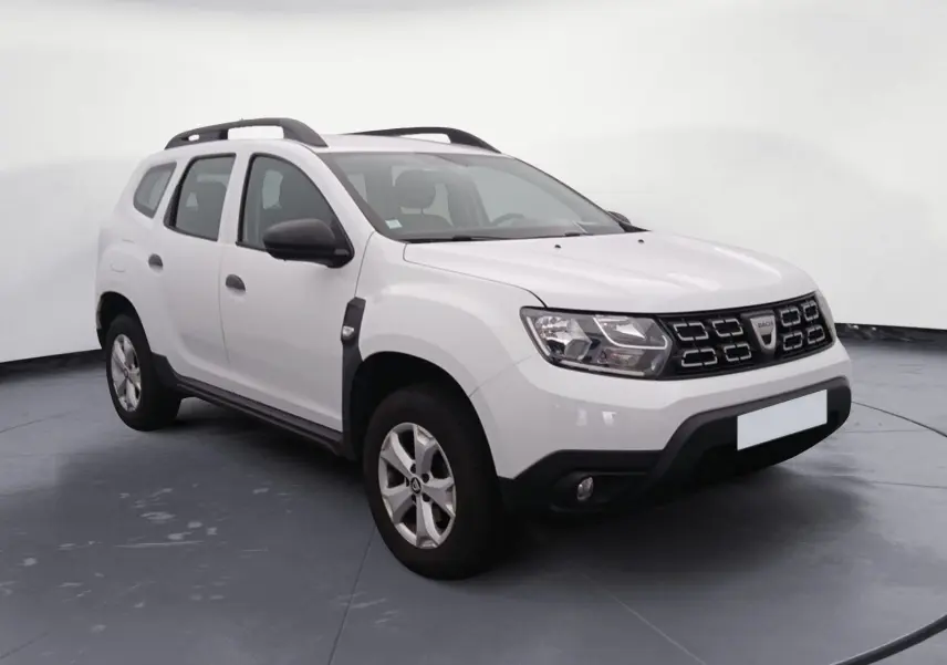 SUV Dacia Duster blanc 4x2 vue 3/4 avant droit avec calandre noire et barres de toit noires.