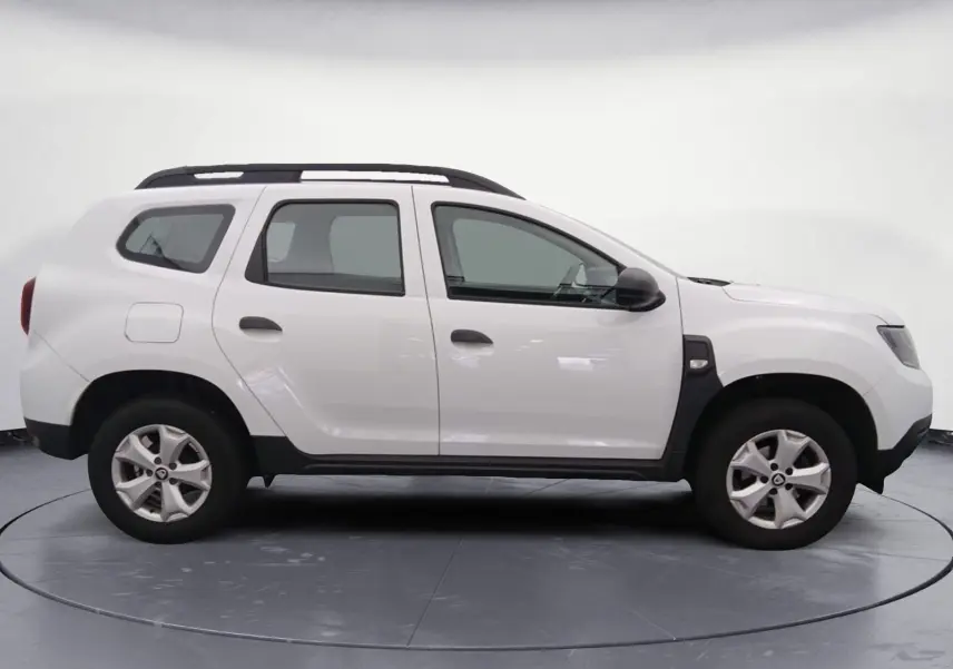 Profil côté gauche d'un Dacia Duster blanc 2021, version 4X2 ECO-G avec jantes alliage et barres de toit noires.