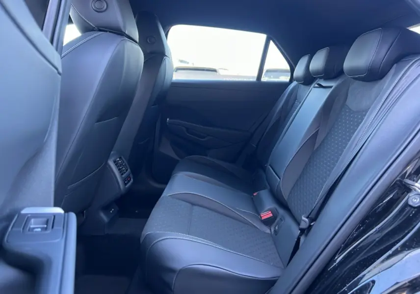 Vue intérieure arrière côté gauche du Volkswagen T-Roc noir ebène 2026, banquette tissu et cuir avec appuie-têtes.