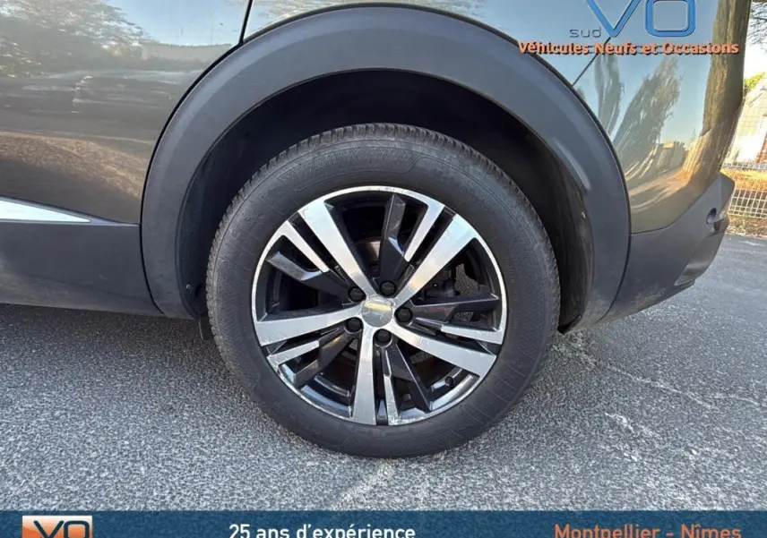 Gros plan sur la roue arrière droite du Peugeot 3008 gris foncé avec jante alliage 18 pouces design bicolore