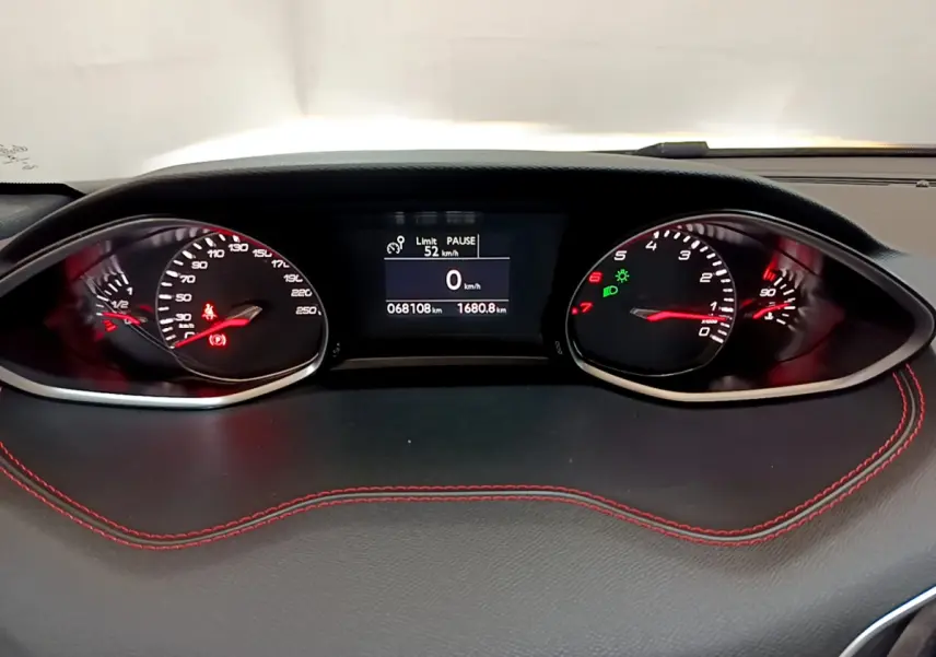 Tableau de bord de Peugeot 308 GT Line 2016, affichage numérique et compteurs analogiques avec surpiqûres rouges visibles.