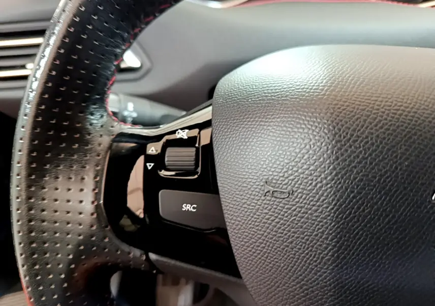 Gros plan sur le volant cuir perforé avec commandes intégrées du Peugeot 308 GT Line gris foncé de 2016.