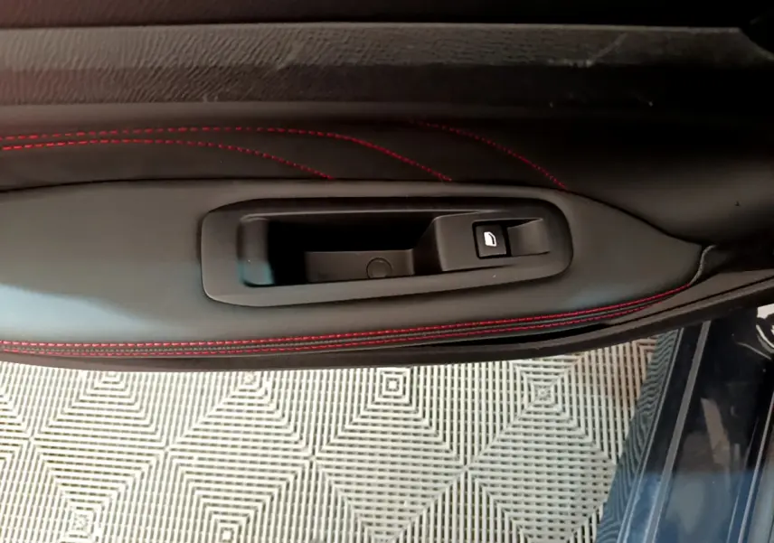 Poignée intérieure côté gauche avec bouton de verrouillage, sur porte en cuir noir à surpiqûres rouges du Peugeot 308 GT Line 2016.