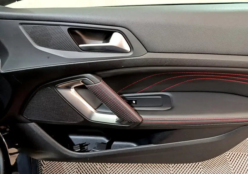 Poignée de porte intérieure côté gauche de Peugeot 308 GT Line 2016 avec surpiqûres rouges et garniture noire.