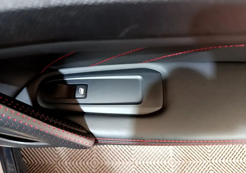 Détail de la poignée de porte intérieure côté gauche de la Peugeot 308 GT Line gris foncé avec surpiqûres rouges.