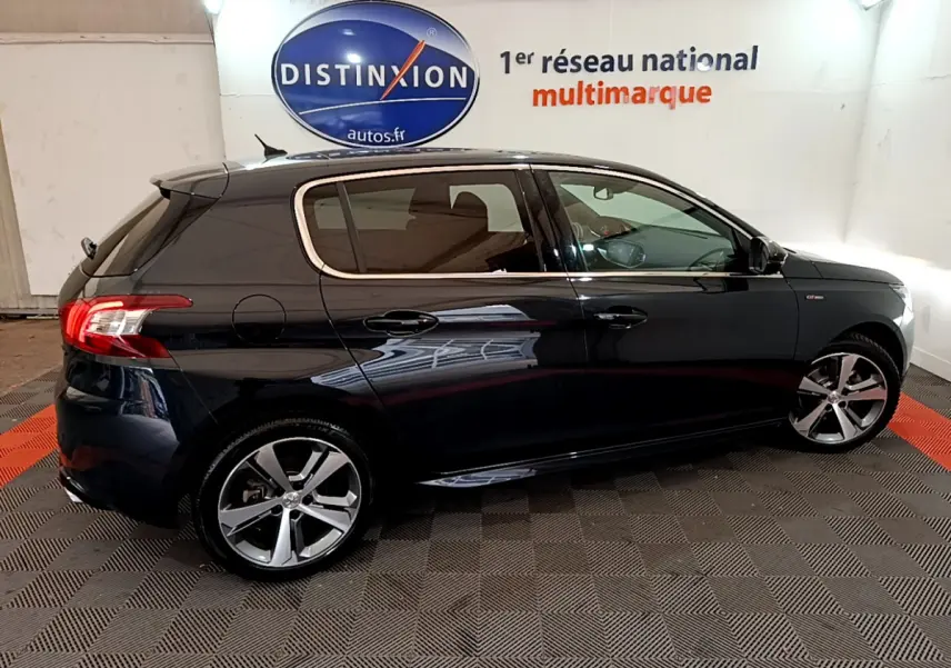 Profil côté droit d'une Peugeot 308 gris foncé GT Line 2016 dans un showroom avec logo Distinxion en arrière-plan