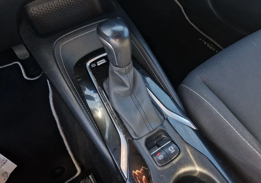 Gros plan sur la console centrale de la Toyota Corolla hybride 2019, montrant le levier de vitesse automatique et les commandes électroniques.