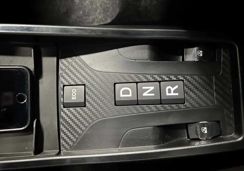 Gros plan sur la console centrale de la Ligier JS50 BEV 8KWH Elite avec boutons boîte auto et finition carbone.