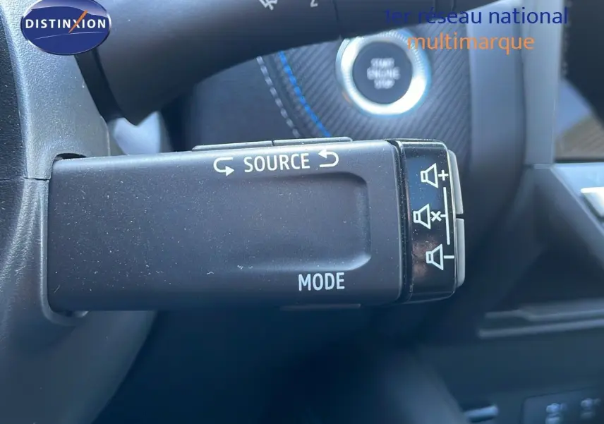 Gros plan sur la commande au volant du Renault Captur E-Tech hybride 2025, avec bouton source et mode visible.