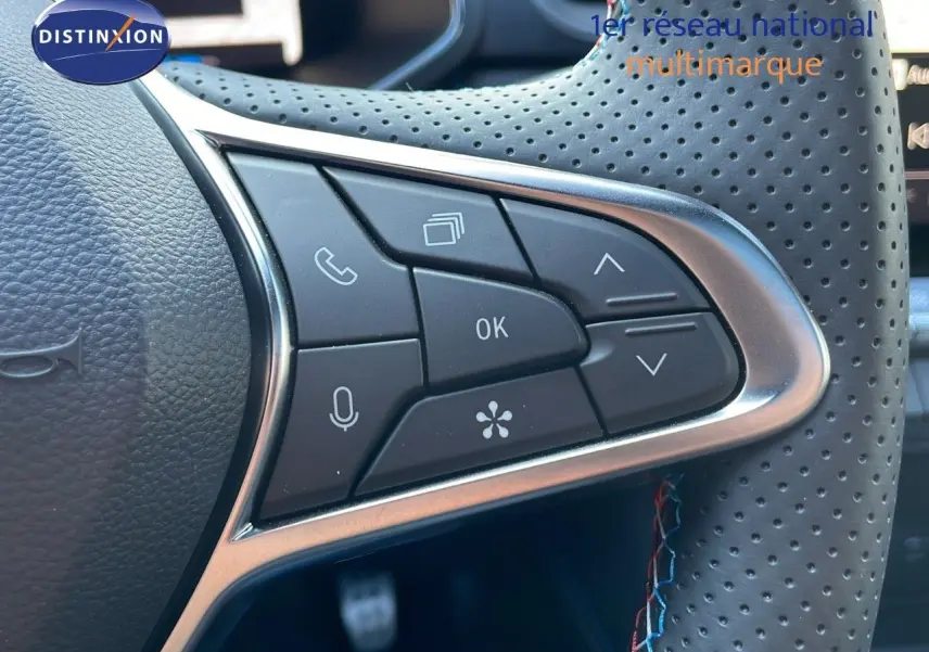 Gros plan sur les commandes multifonctions au volant perforé du Renault Captur E-Tech hybride 2025, finition Esprit Alpine.