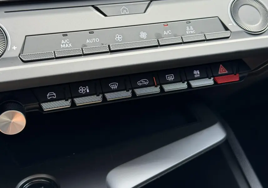 Gros plan sur la console centrale du Peugeot 308 SW 2025 gris Selenium, montrant les commandes climatisation et boutons fonctionnels.
