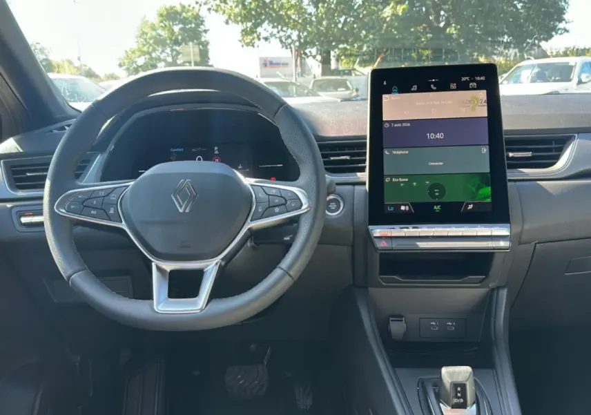 Vue intérieure frontale du tableau de bord du Renault Captur gris cassiopée, avec volant multifonction et écran tactile vertical.