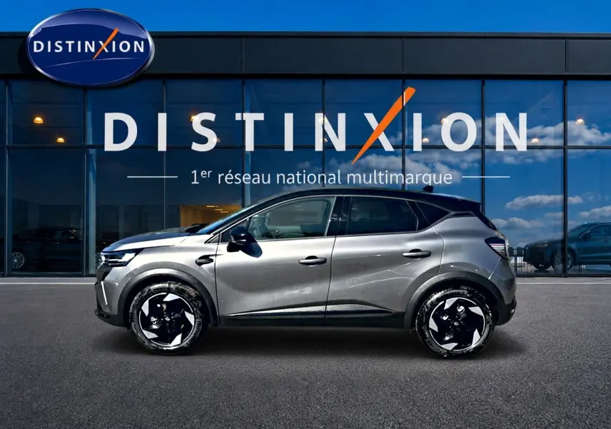 Renault Captur 1.8 e-tech full hybrid 2026 gris cassiopée vu de profil droit devant une vitrine Distinxion.