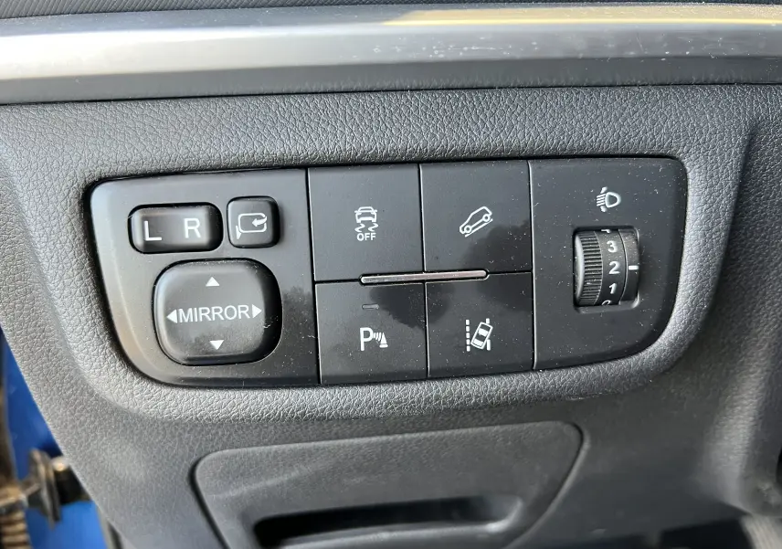 Panneau de commandes noir avec réglages des rétroviseurs, contrôle de stabilité et réglage des phares dans un SERES 3 électrique.