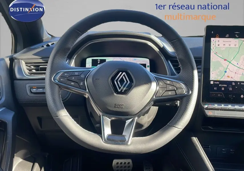 Vue intérieure centrée sur le volant cuir perforé du Renault Captur E-Tech 2025 avec écran tactile et tableau de bord numérique.