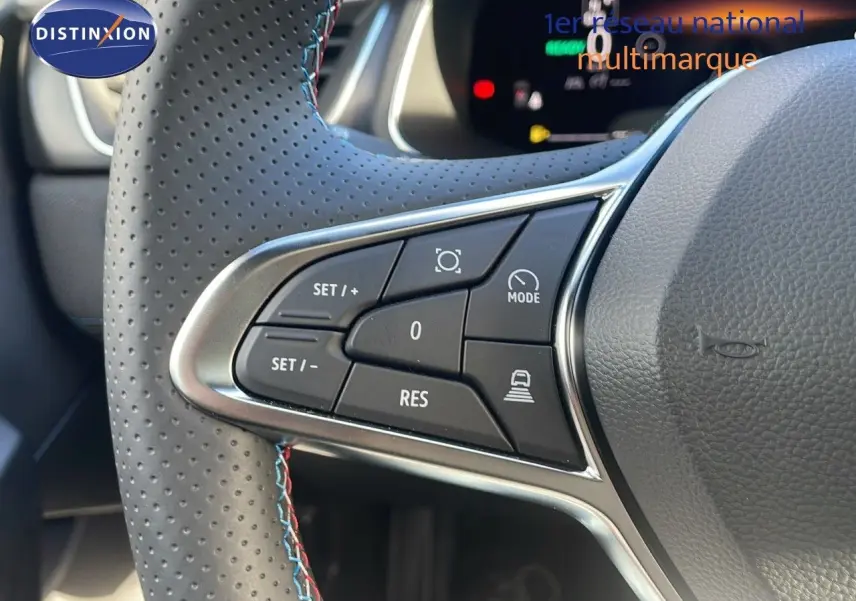 Gros plan sur les commandes au volant en cuir perforé gris avec surpiqûres bleues du Renault Captur E-Tech hybride 2025.