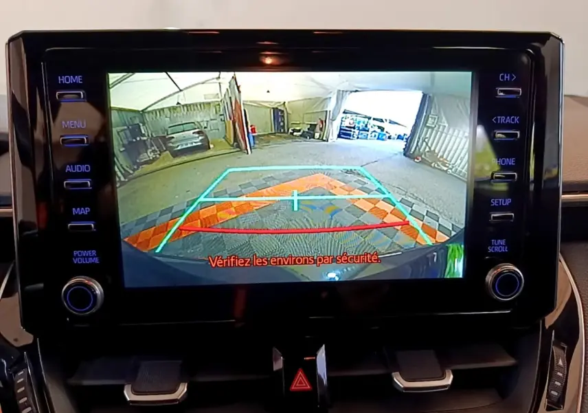 Écran tactile central montrant la caméra de recul avec guidage coloré sur Toyota Corolla noire hybride 2021.