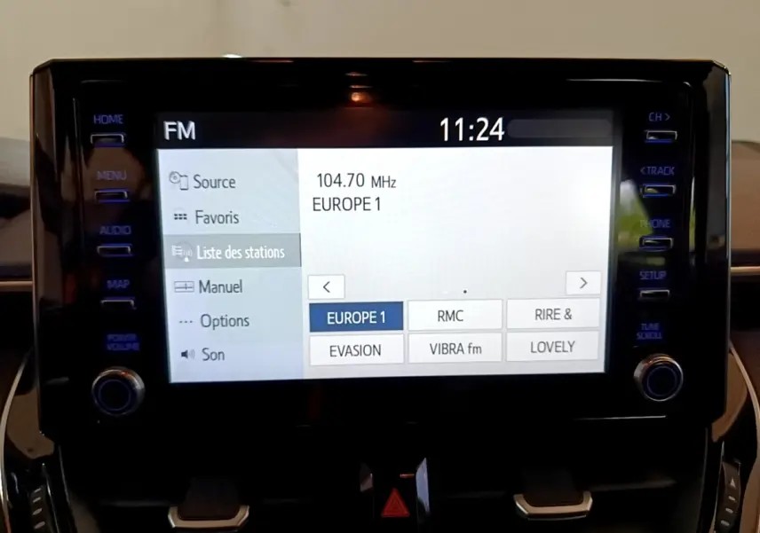 Écran tactile central de la Toyota Corolla hybride noire 2021 affichant la liste des stations radio FM à 11h24.