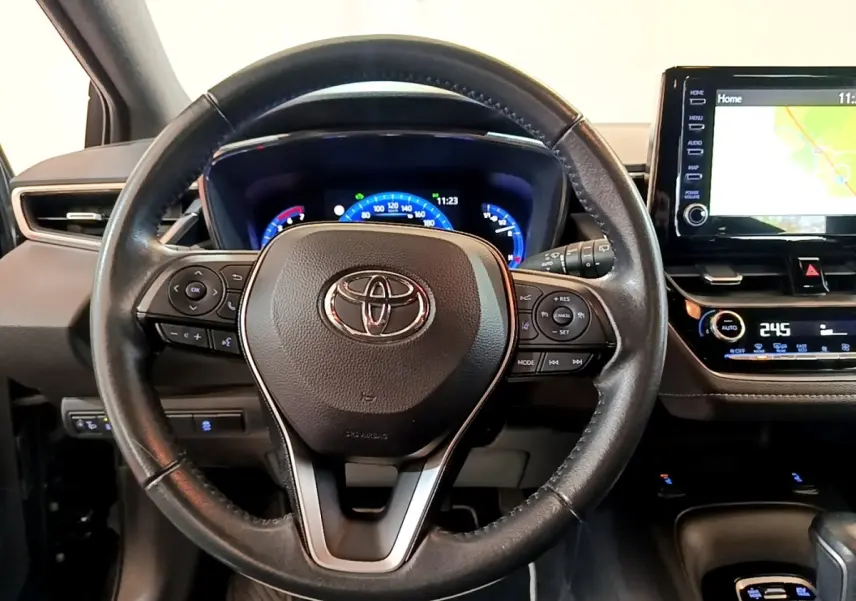 Vue frontale du volant en cuir noir de la Toyota Corolla Hybride 2021 avec tableau de bord digital et écran tactile navigation.