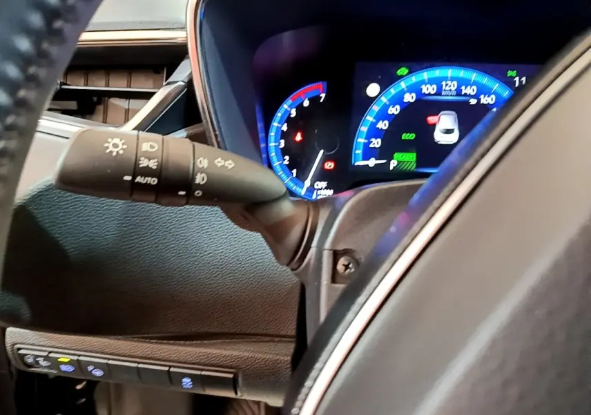 Gros plan sur le tableau de bord numérique bleu et noir de la Toyota Corolla hybride 2021, avec commandes d'éclairage visibles.