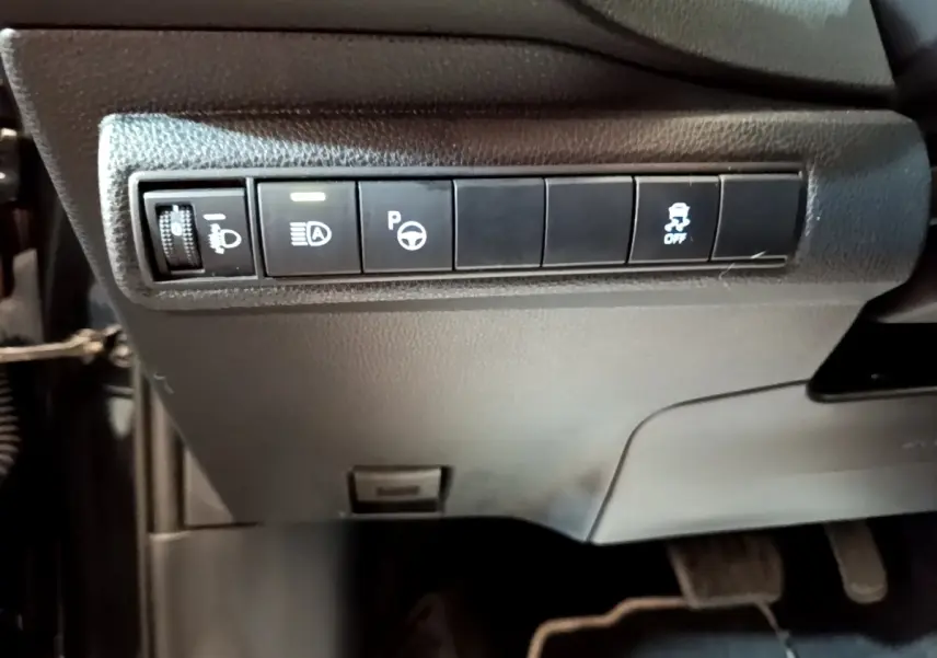 Gros plan sur les commandes noires sous le tableau de bord de la Toyota Corolla hybride 2021, côté conducteur.