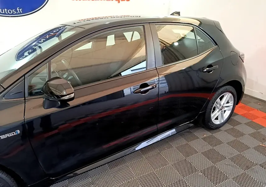 Profil côté gauche de la Toyota Corolla hybride noire 2021, mettant en valeur les jantes alliage et le badge Hybrid.