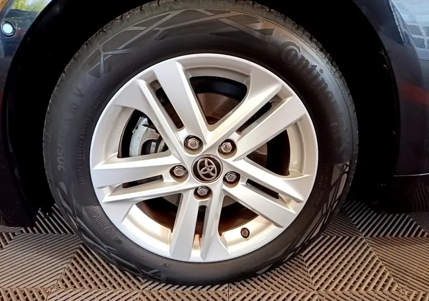 Gros plan sur la roue avant droite d'une Toyota Corolla noire, mettant en valeur la jante alliage et le logo Toyota central.