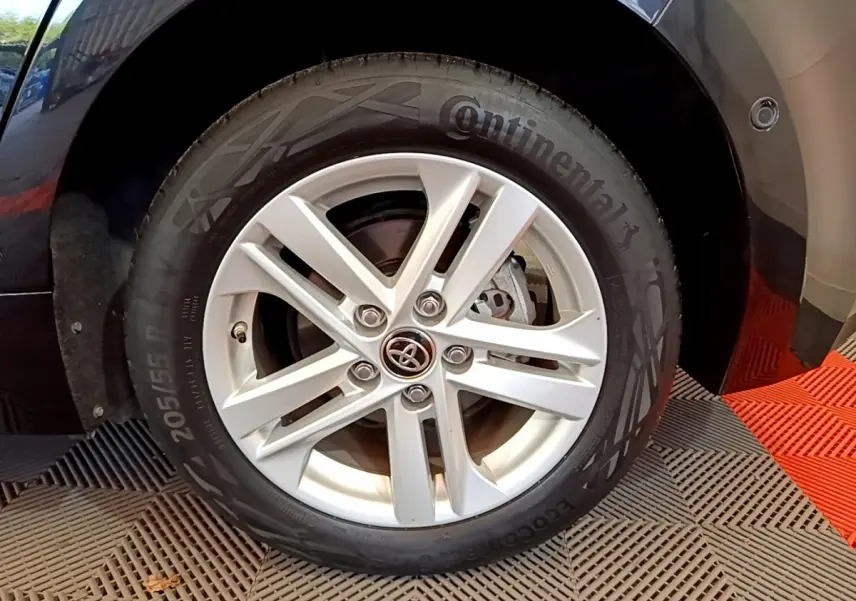 Gros plan sur la roue avant droite noire d'une Toyota Corolla hybride avec jante argentée et pneu Continental.