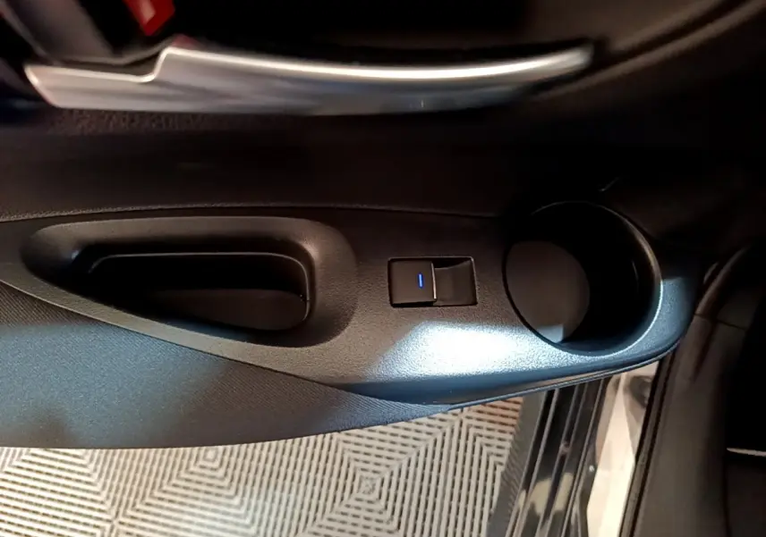 Poignée de porte intérieure côté conducteur noire avec bouton de verrouillage éclairé sur Toyota Corolla hybride 2021.