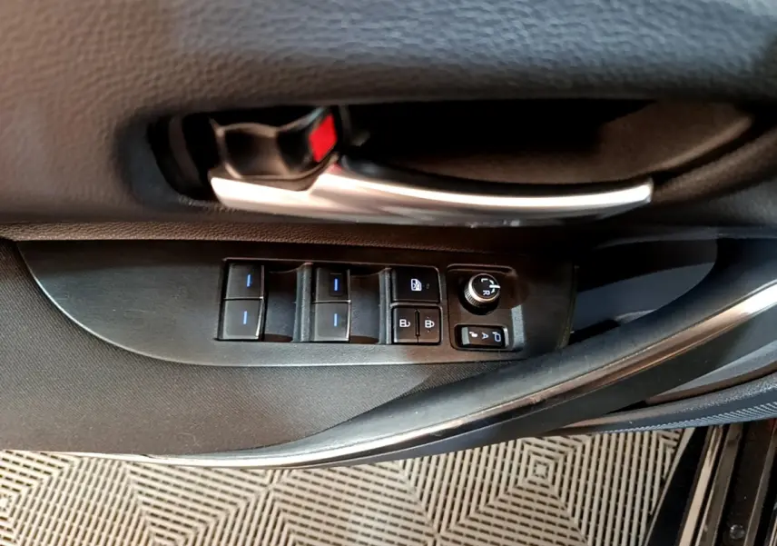 Gros plan sur la commande des vitres et rétroviseurs côté conducteur d'une Toyota Corolla noire hybride 2021.