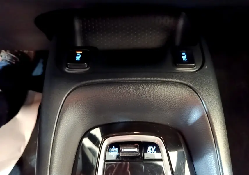 Gros plan sur la console centrale noire de la Toyota Corolla hybride, montrant les boutons Drive Mode et EV Mode.