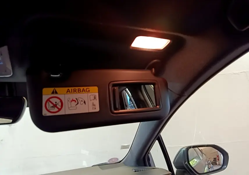 Miroir de courtoisie sur pare-soleil côté conducteur d'une Toyota Corolla hybride noire, vue intérieure avant droite.