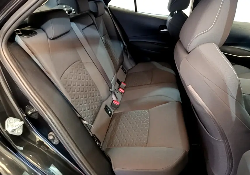 Vue intérieure côté gauche des sièges arrière noirs en tissu de la Toyota Corolla hybride 2021 avec motifs géométriques.