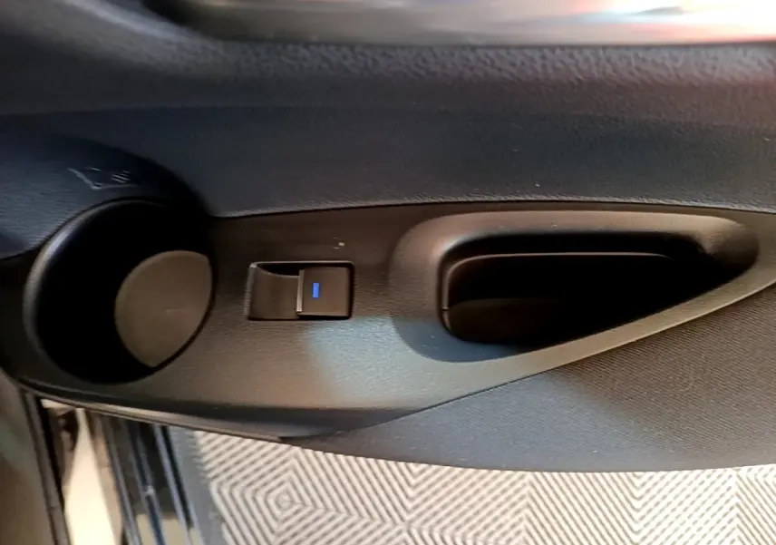 Poignée intérieure de porte côté gauche avec bouton de verrouillage, sur Toyota Corolla hybride noire 2021.