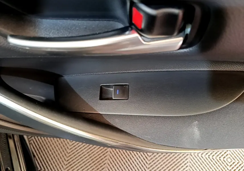 Gros plan sur la poignée intérieure et bouton de verrouillage de la porte côté gauche d'une Toyota Corolla noire hybride 2021.