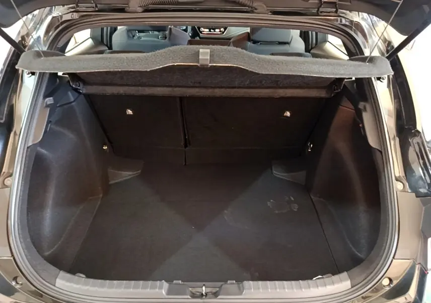 Coffre ouvert d'une Toyota Corolla hybride noire, vue arrière montrant l'espace de chargement et la tablette de séparation.