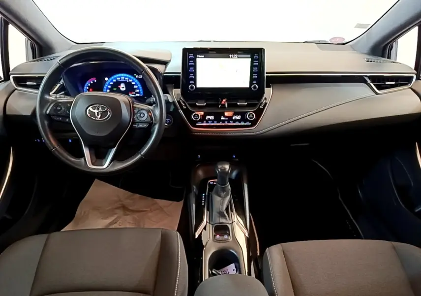 Intérieur noir de la Toyota Corolla hybride 2021, vue frontale du tableau de bord avec écran tactile et volant multifonctions.