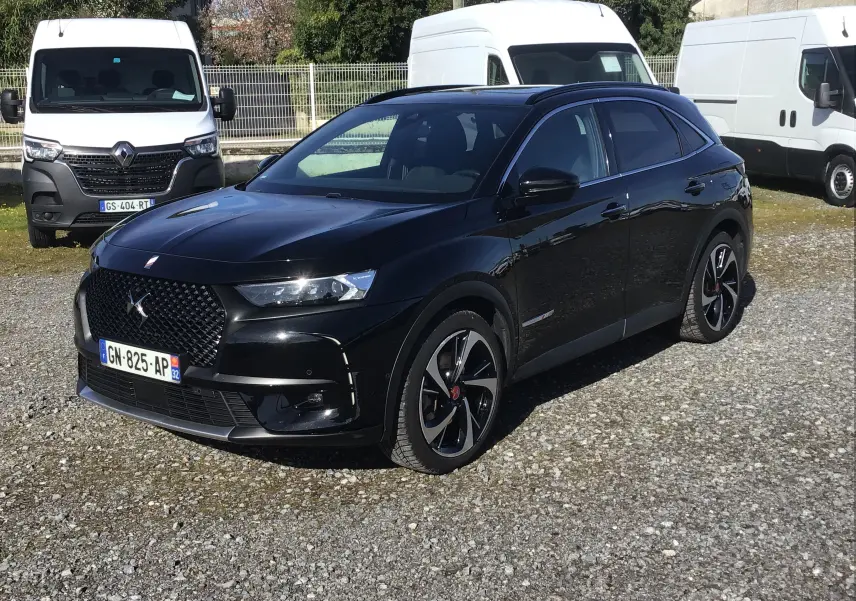 DS7 Crossback noir en 3/4 avant droit, avec jantes distinctives et calandre au design élégant, stationné sur sol gravillonné.