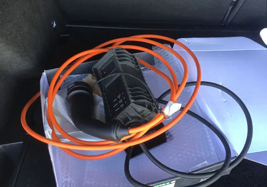 Gros plan sur le coffre d’un DS7 Crossback noir 2023, montrant un câble de recharge orange et noir enroulé.