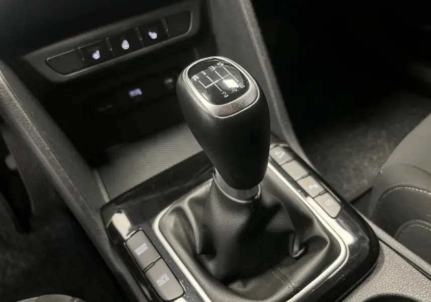 Le levier de vitesses manuel noir du Kia Sportage 2022, entouré de commandes et console centrale sombre.
