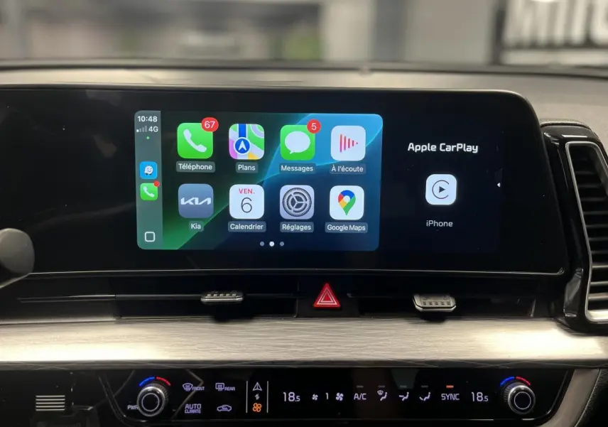 Écran tactile central affichant Apple CarPlay dans l'habitacle du Kia Sportage gris, vue rapprochée du tableau de bord.