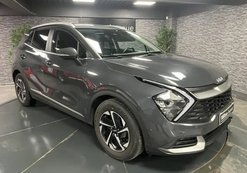KIA SPORTAGE gris métallisé en 3/4 avant droit avec calandre noire laquée et jantes alliage 17 pouces.
